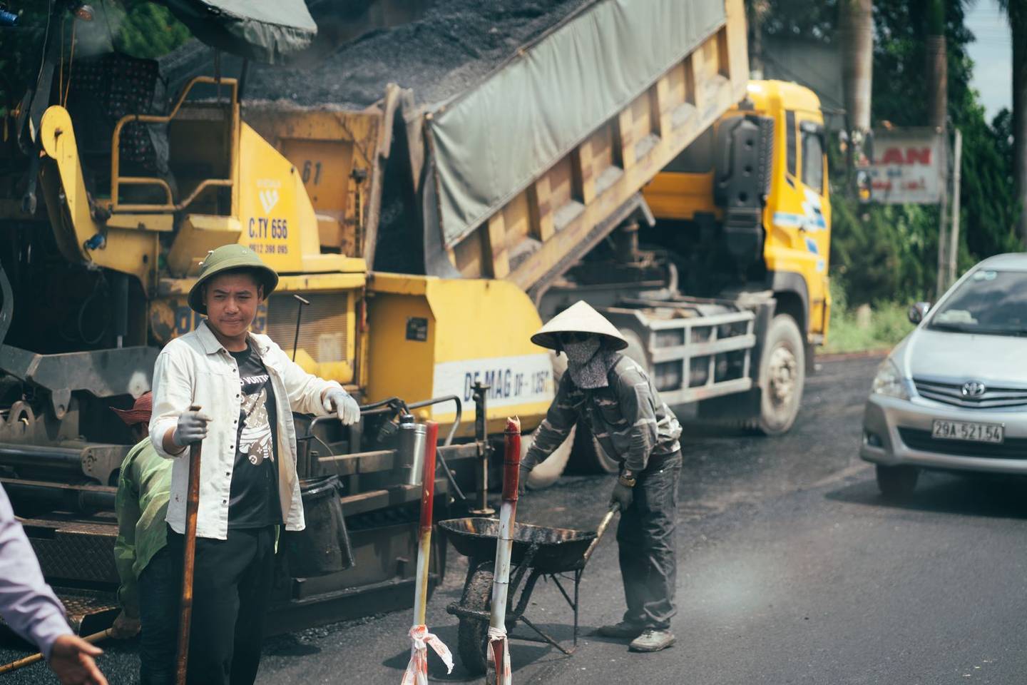 Crew paving a road, illustrating repair versus resurfacing